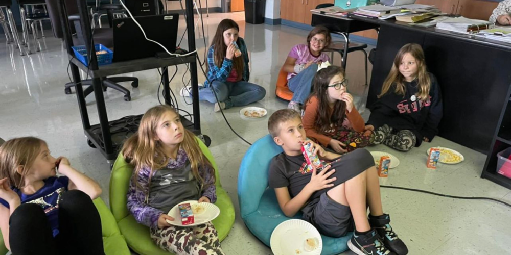 Second grade students sitting on the floor and watching a movie