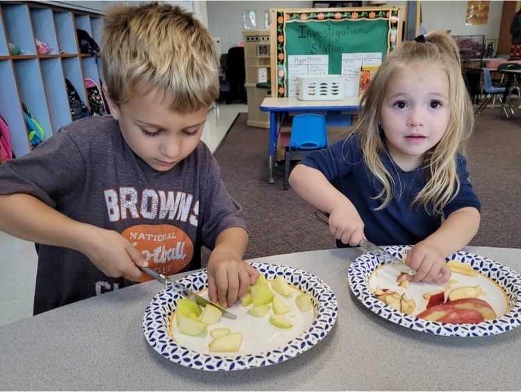 two preschool students tasting apples 